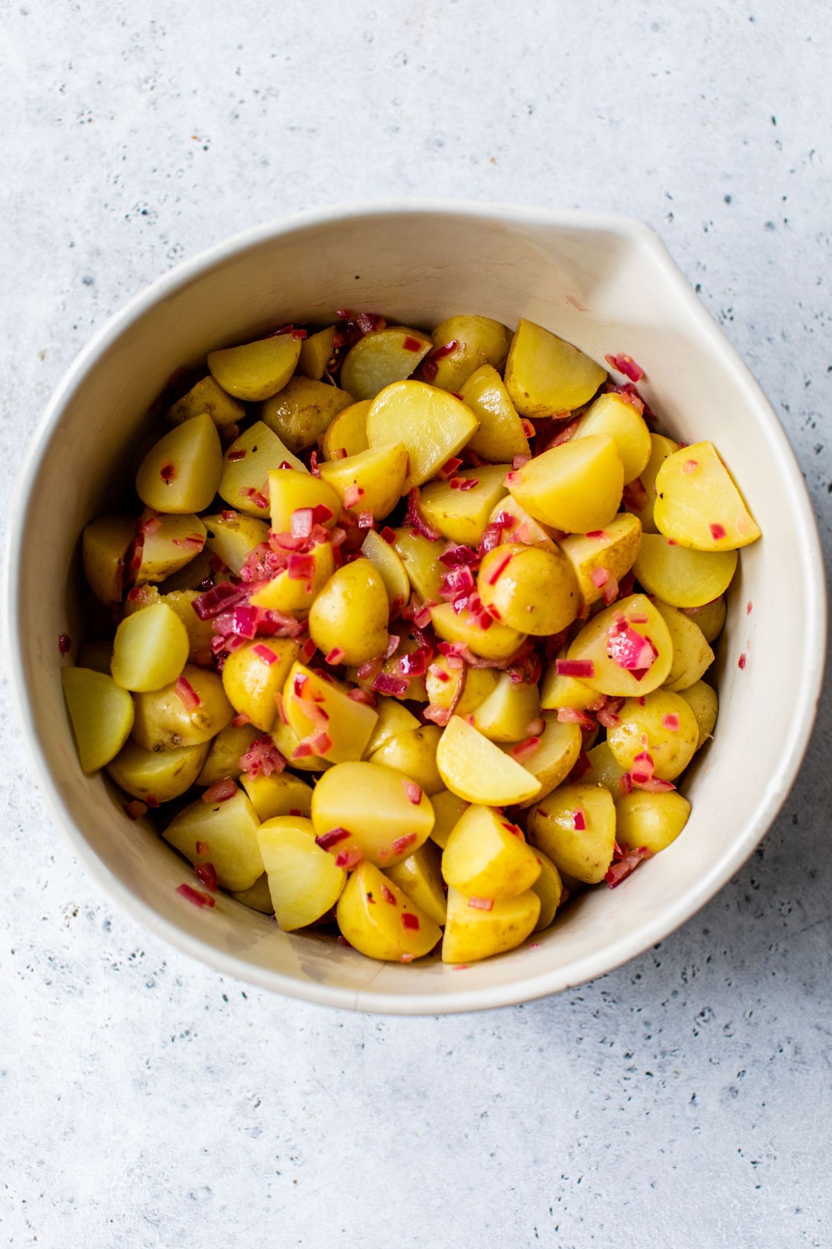 Combining dressing with cooked red potatoes.