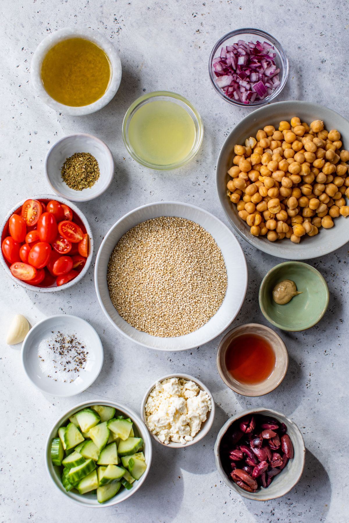 Ingredients for making a Greek Quinoa Salad divided into small bowls.