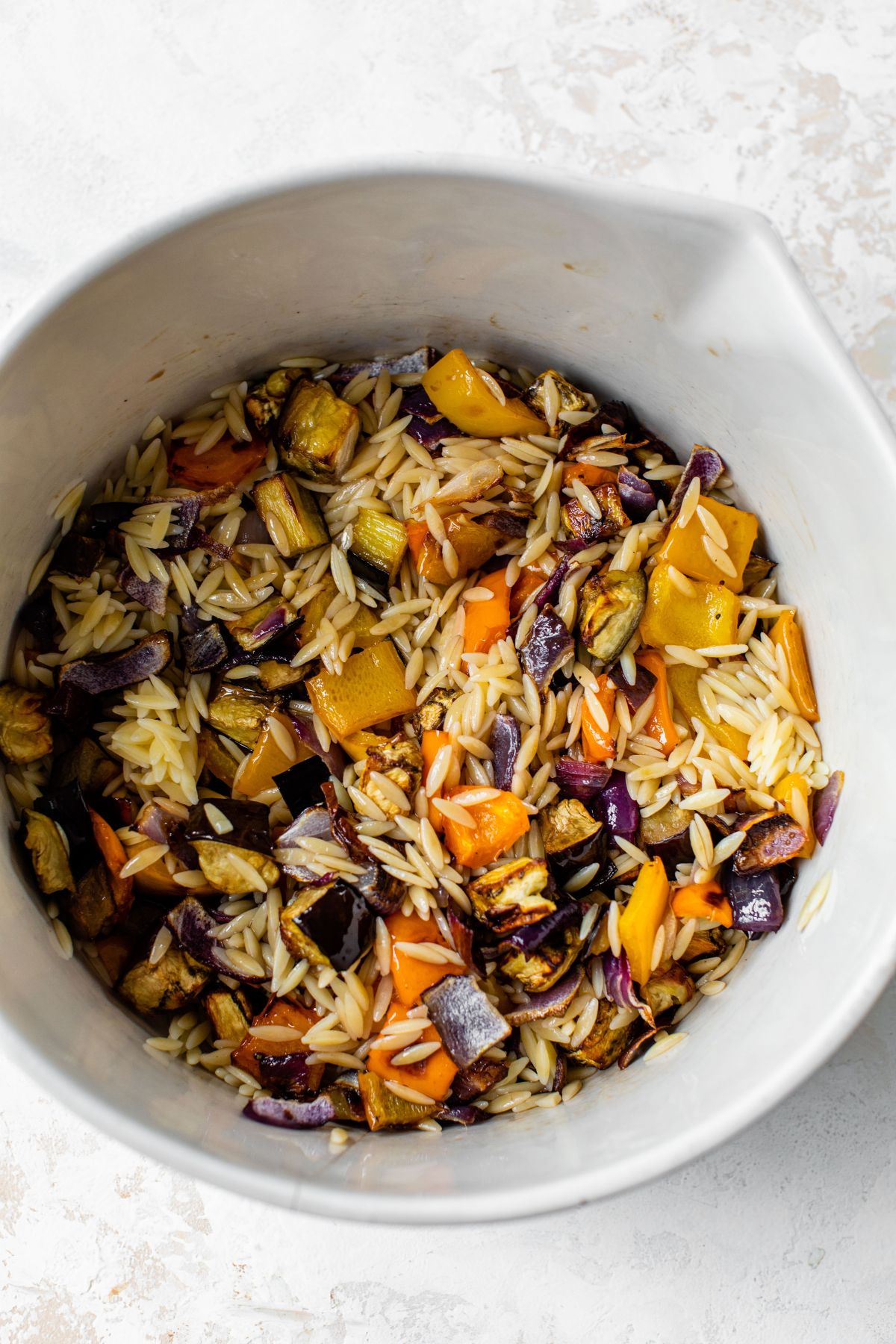 Stirring together orzo with roasted veggies.