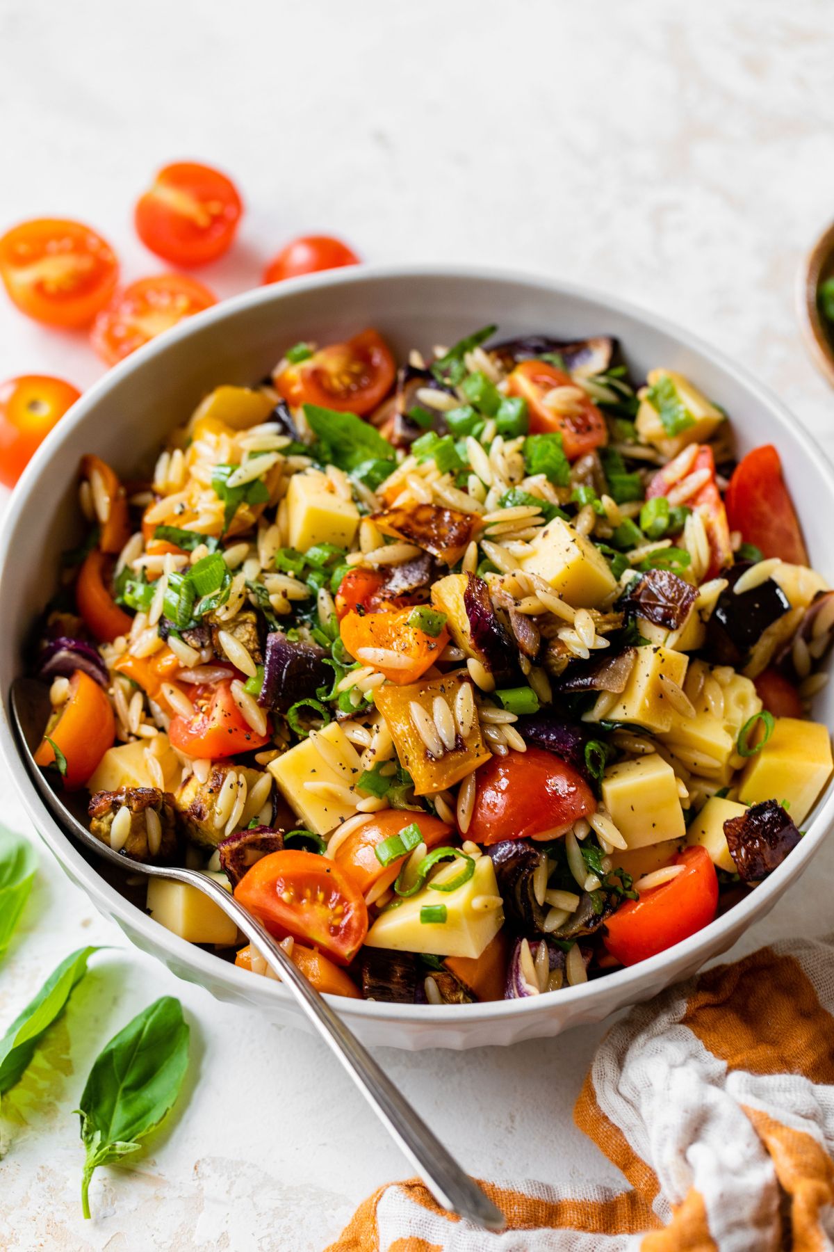 Orzo pasta salad with roasted veggies in a white bowl.