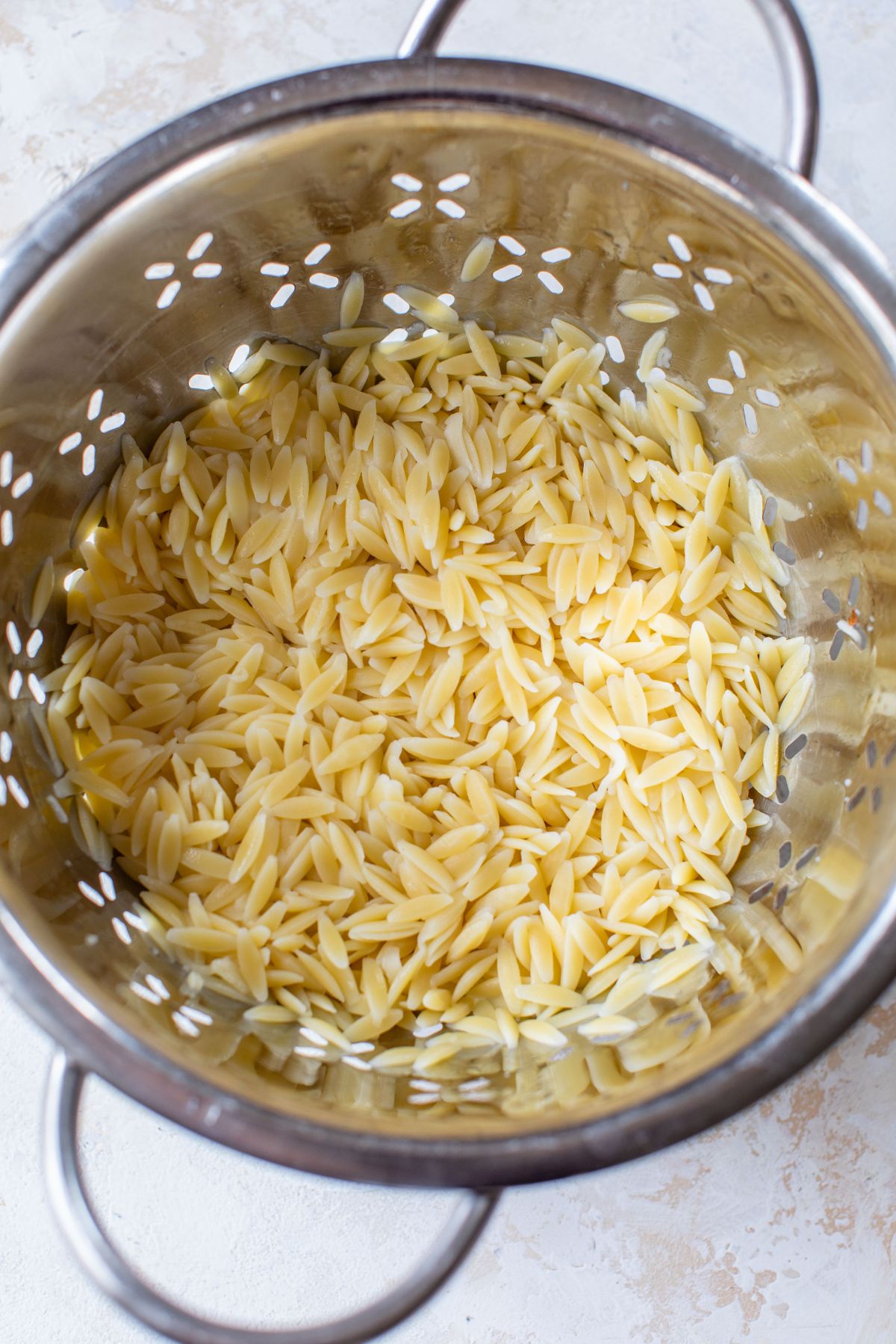 Draining orzo pasta in a colander. 