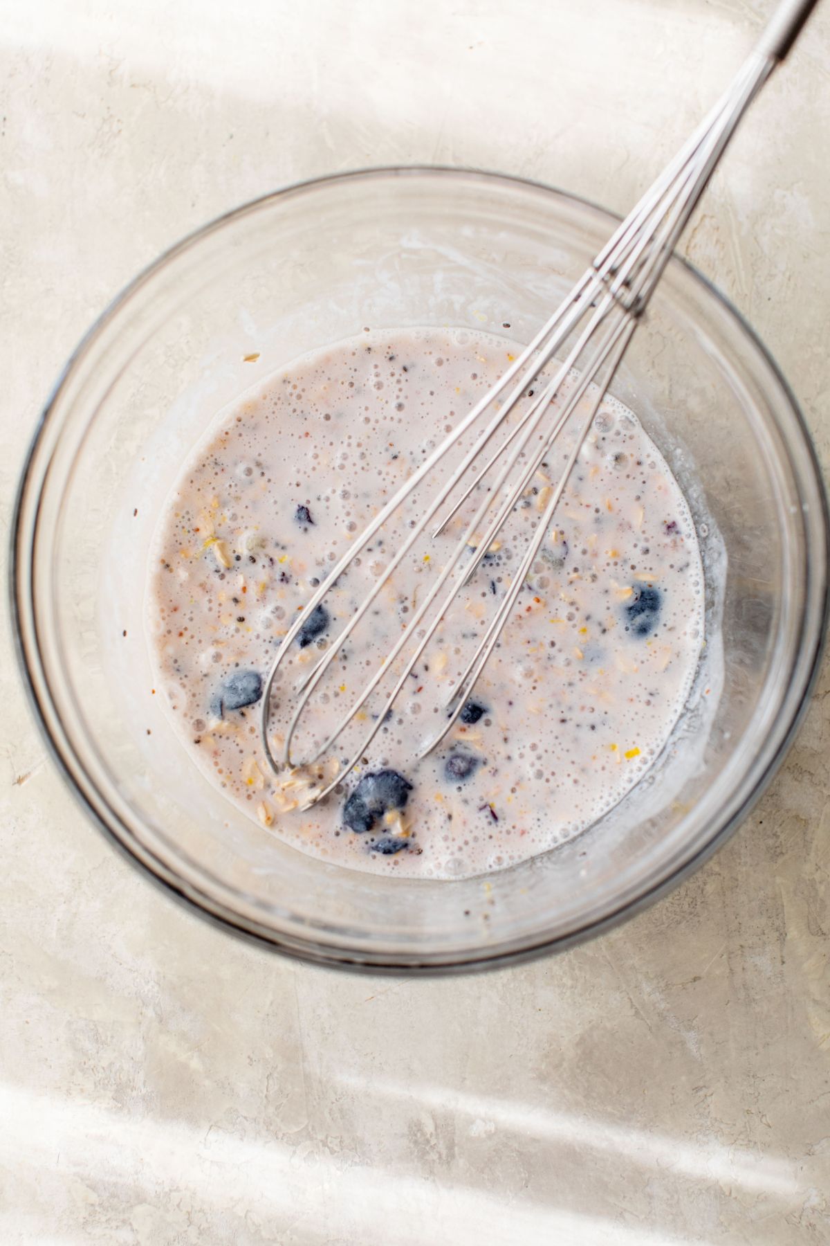 Whisking oats with milk, Greek yogurt, blueberries and lemon zest in a large bowl.