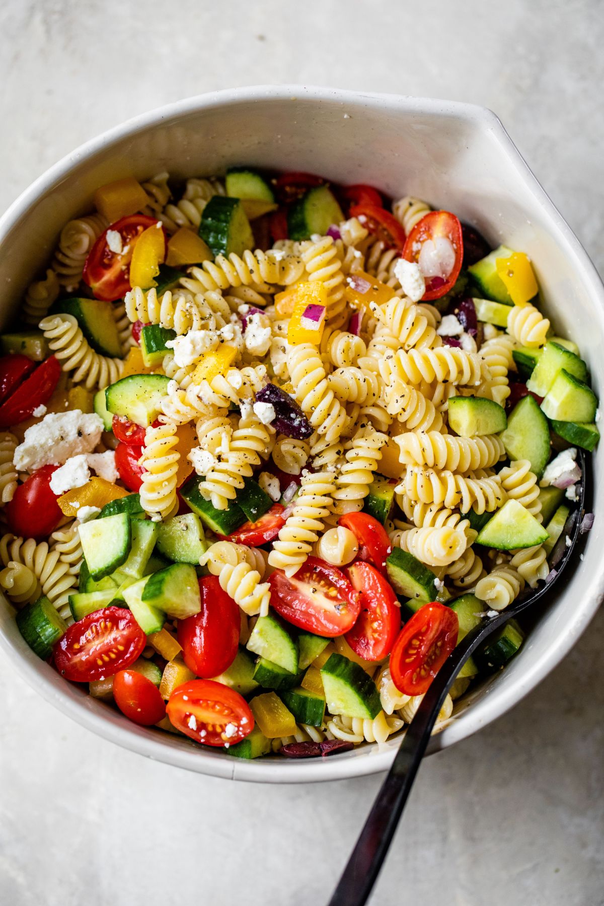 Greek pasta salad tossed in a large bowl.