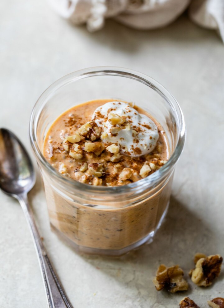 Pumpkin overnight oats in a glass jar topped with nuts and yogurt.