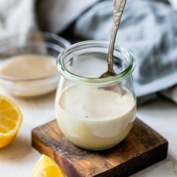 Small jar of lemon tahini dressing with a spoon inside.