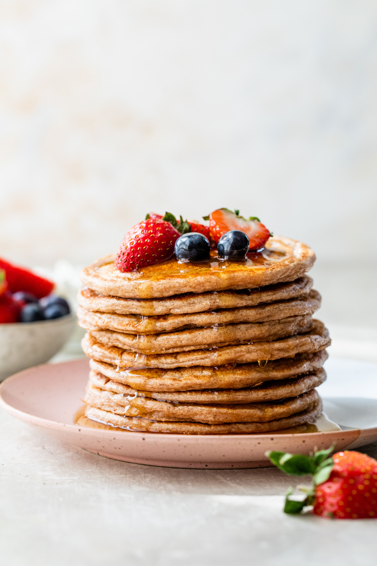 Stack of cottage cheese pancakes topped with berries and maple syrup