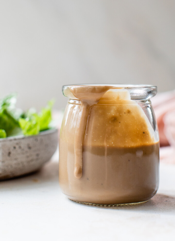 creamy balsamic dressing in a glass jar with salad greens