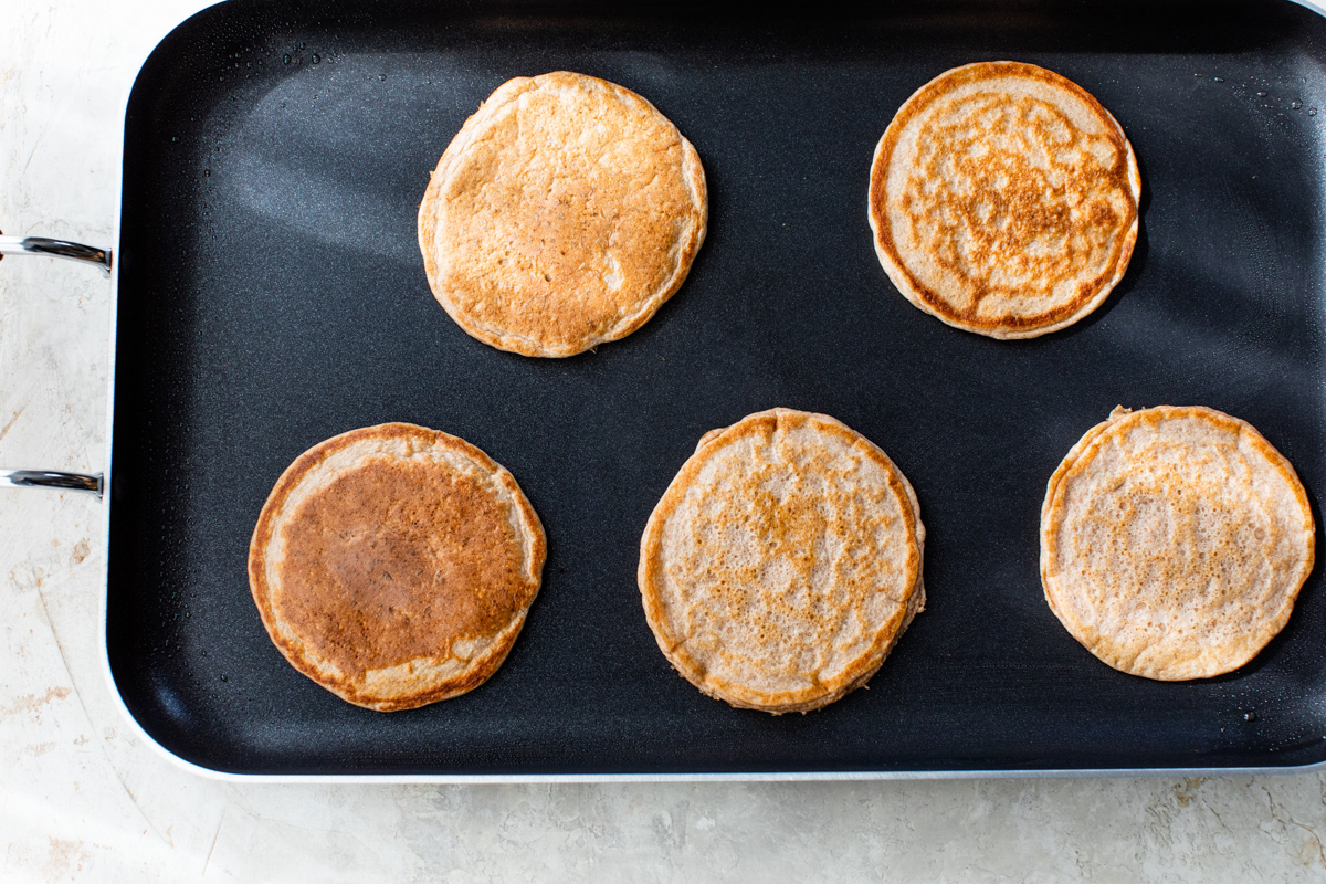 Cottage cheese pancakes cooking on a pancake griddle.