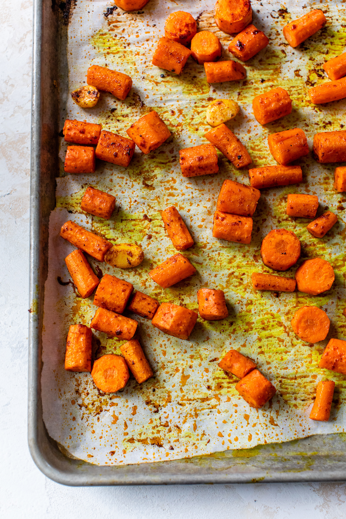 seasoned carrots and garlic on a roasting pan