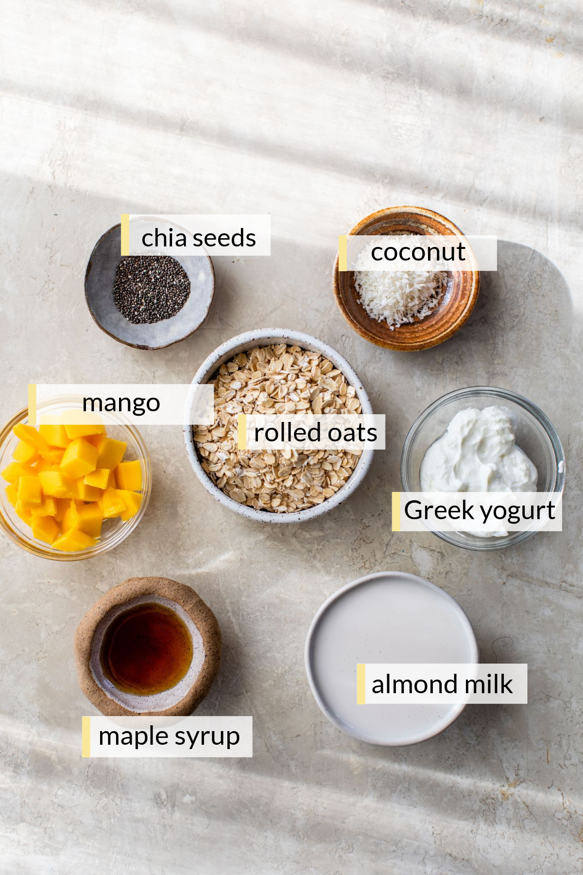 Ingredients for mango overnight oats divided into small bowls.