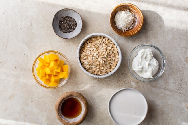 Ingredients for mango overnight oats divided into small bowls.
