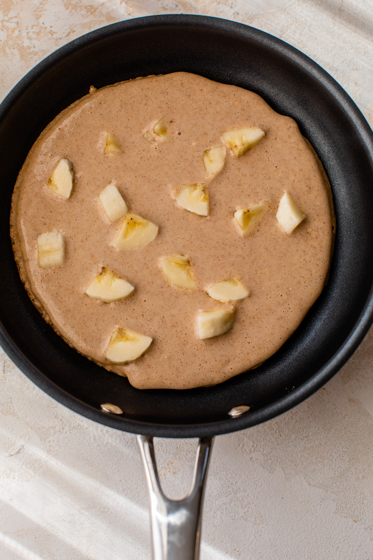 banana peanut butter pancakes cooking in a 8-inch pan