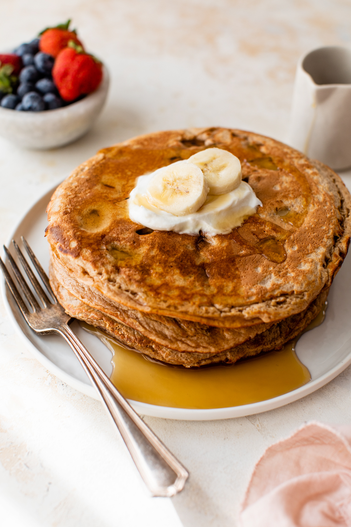 Banana peanut butter protein pancakes topped with yogurt and maple syrup