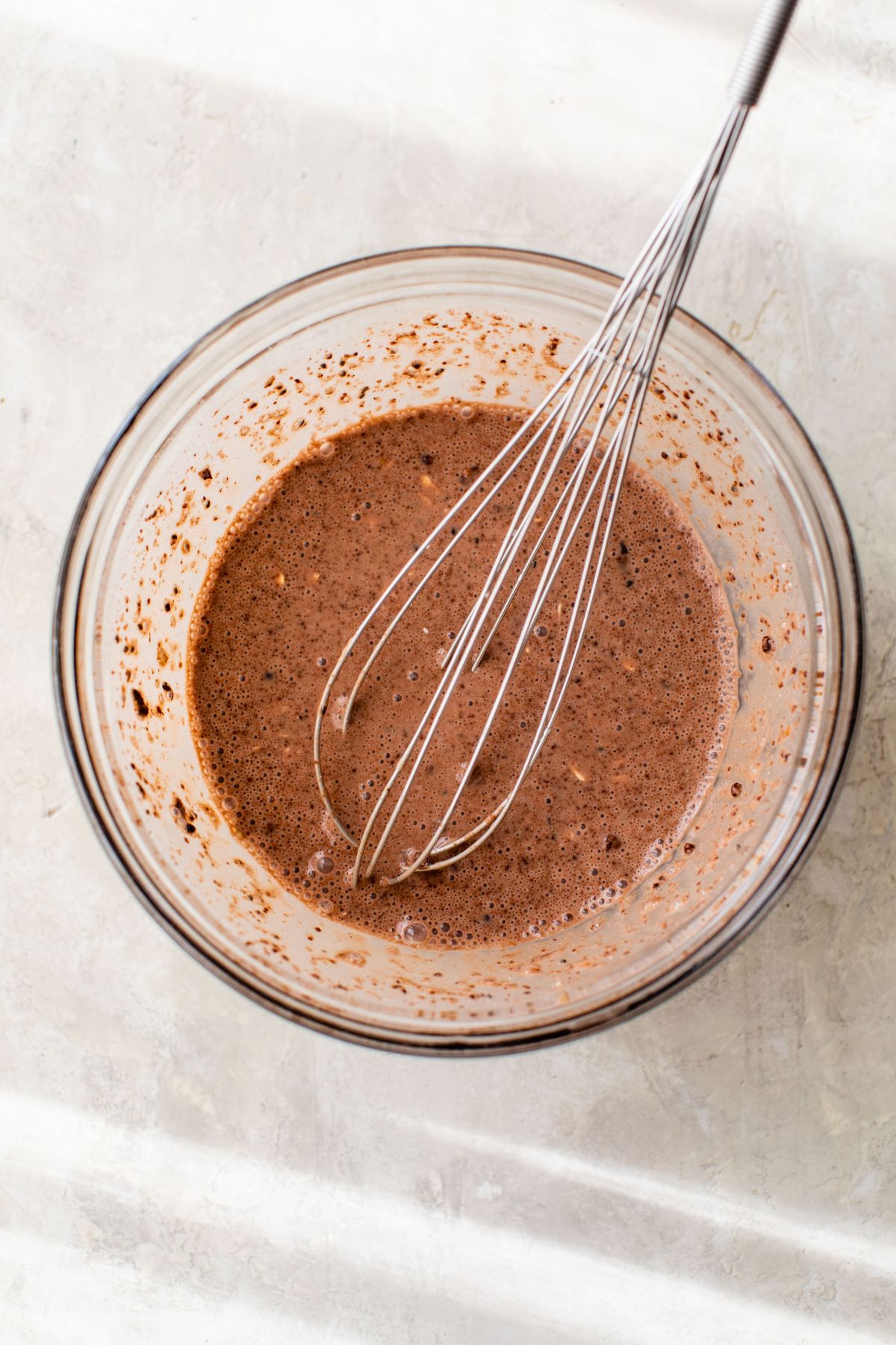 Whisking cocoa powder into overnight oats in a large bowl.
