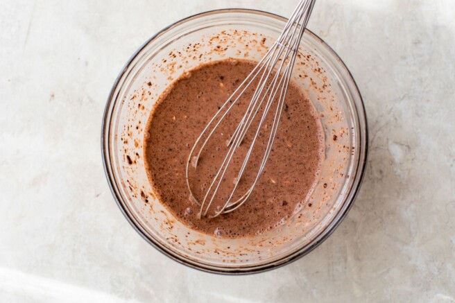 Whisking cocoa powder into overnight oats in a large bowl.
