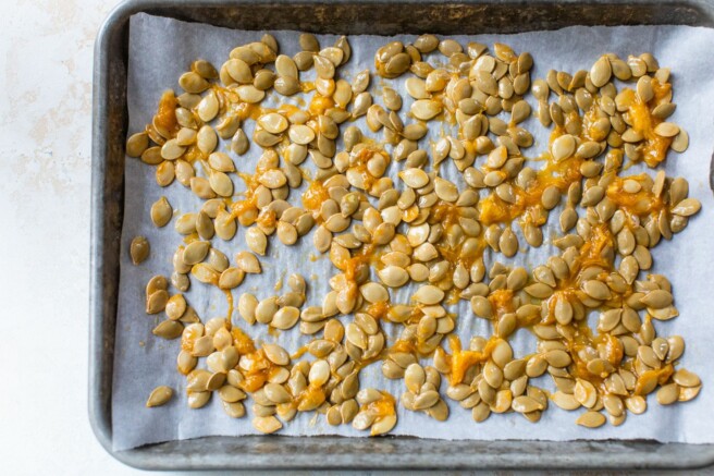 Spreading acorn squash seeds out evenly over pan.