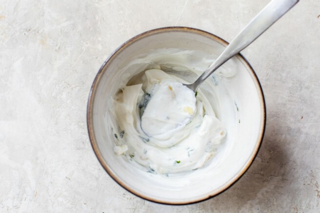 Stirring together Greek yogurt with garlic and parsley.