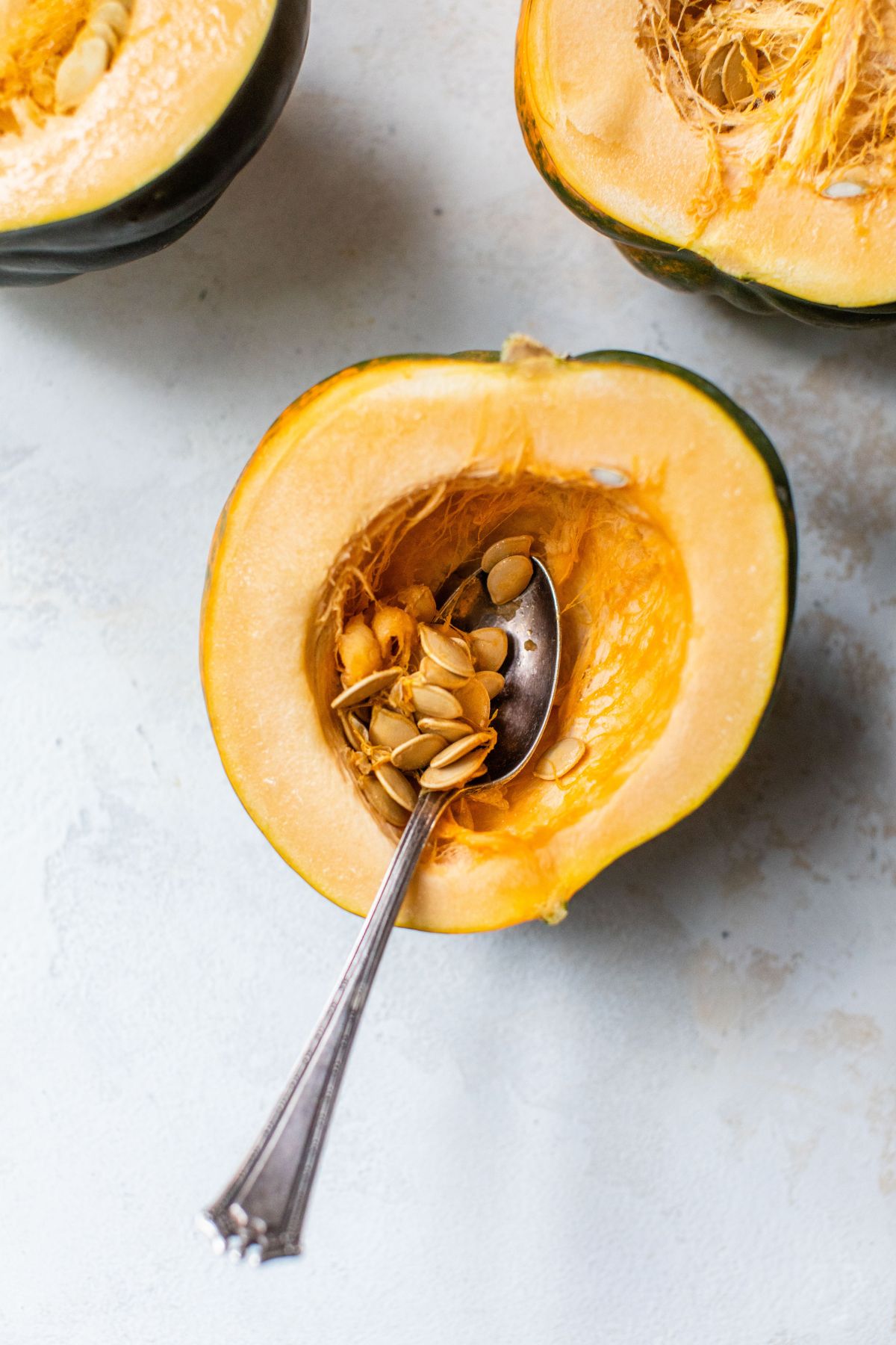 Using a spoon to remove seeds from an acorn squash.