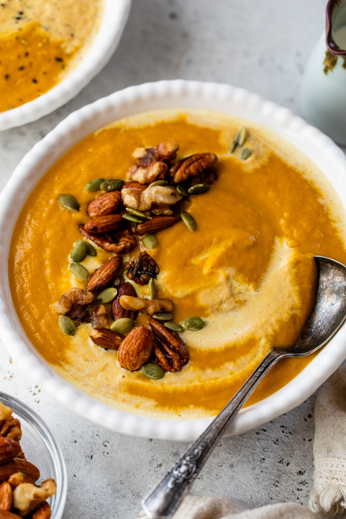 pumpkin curry soup topped with coconut milk and spiced nuts