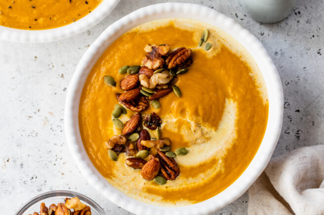 30 minute pumpkin curry soup in bowl topped with spiced nuts