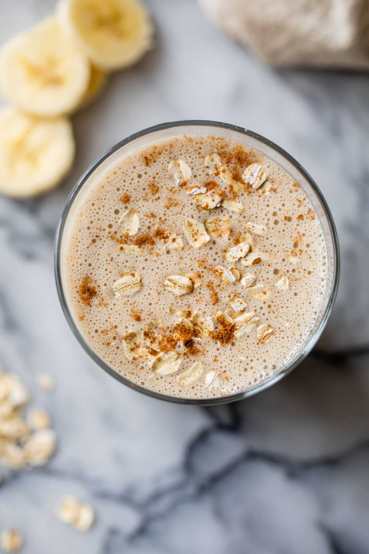 Top view of an oatmeal smoothie topped with a sprinkle of oats and cinnamon.