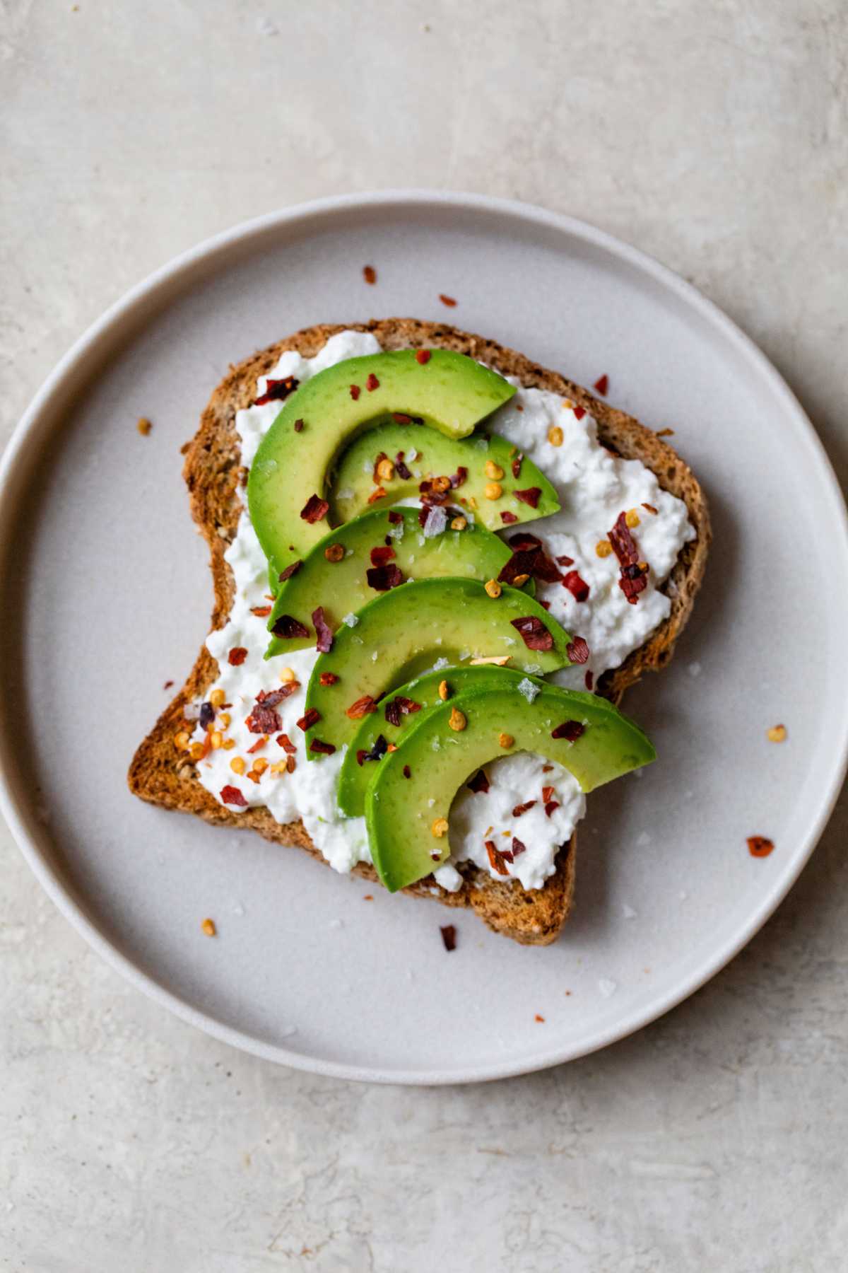 Toast topped with cottage cheese, avocado and red pepper flakes.