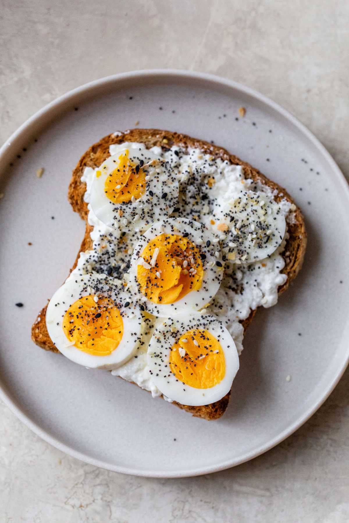 Cottage cheese toast topped with cottage cheese and sliced hard-boiled eggs on a plate.