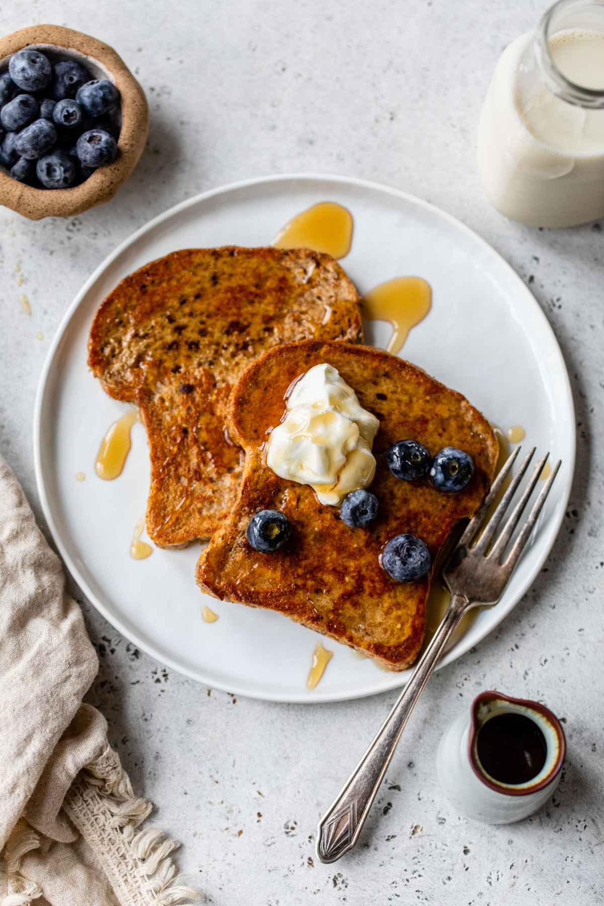 French toast on a plate topped with Greek yogurt and blueberries.