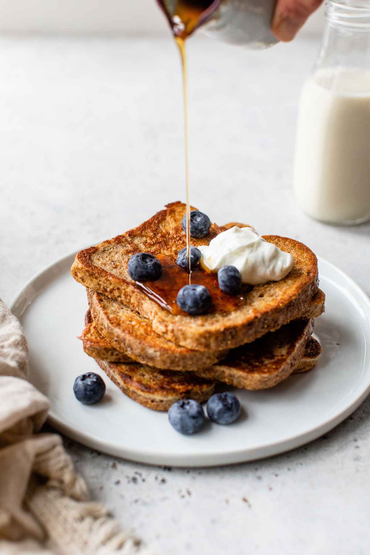 Drizzling maple syrup over a plate with protein French toast.