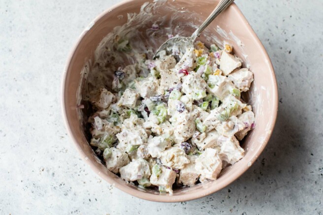 Mixing cranberry-walnut chicken salad in a large bowl.
