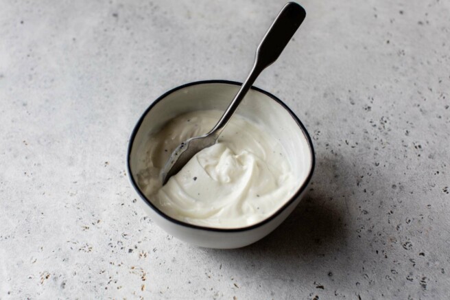 Stirring mayo with yogurt and lemon juice in a small bowl.