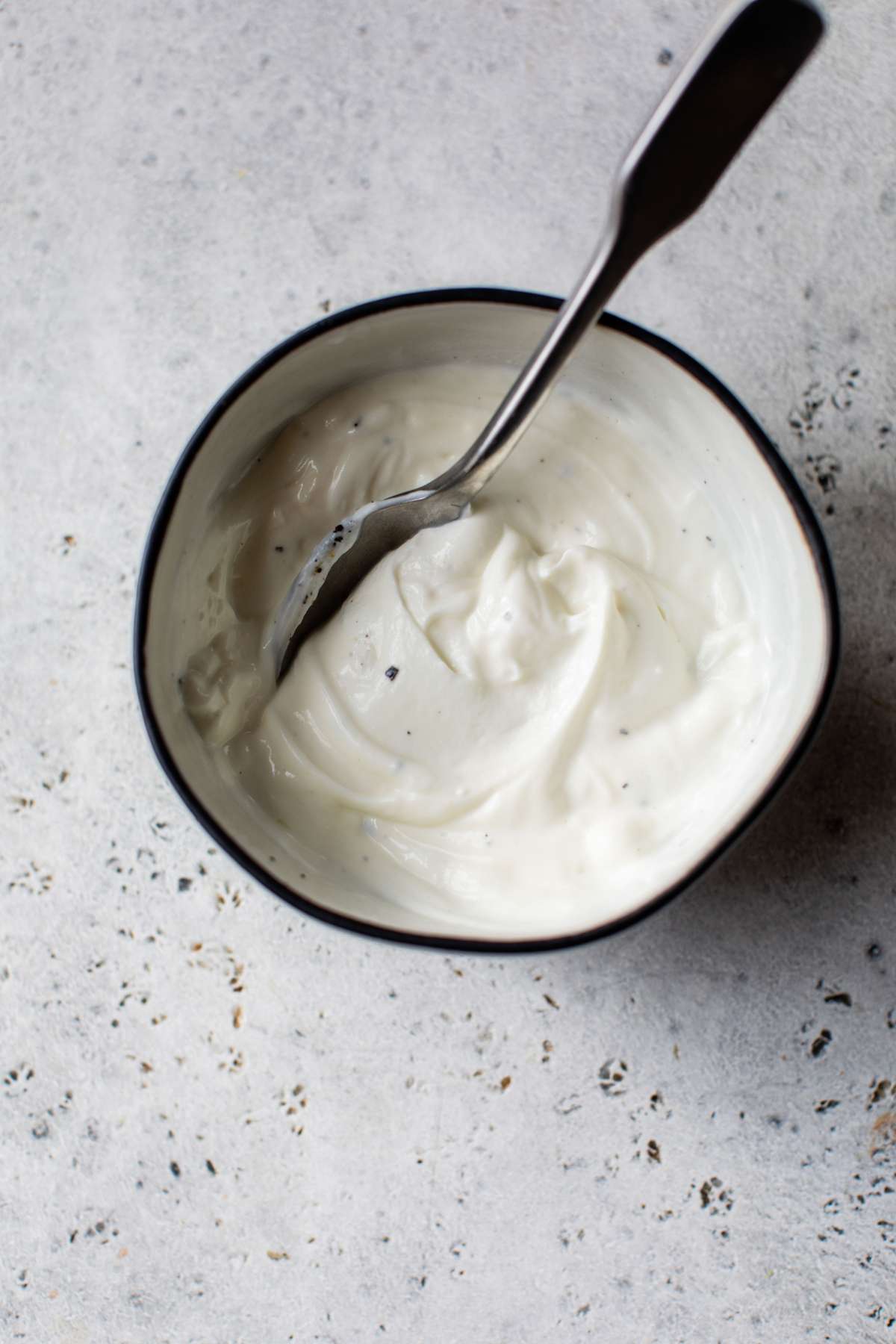 Stirring mayo with yogurt and lemon juice in a small bowl.