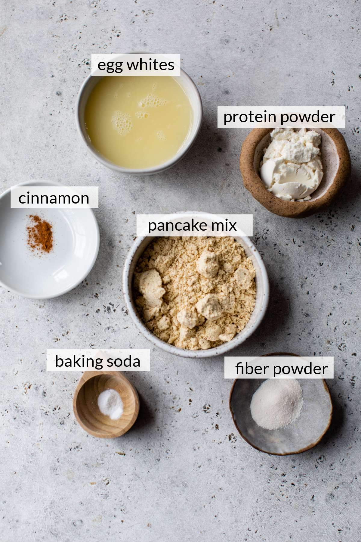 Small bowls with pancake mix, egg whites, protein powder, baking powder and cinnamon.