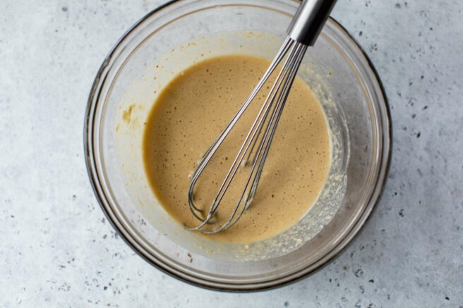 Using a whisk to mix pancake batter in a large bowl.