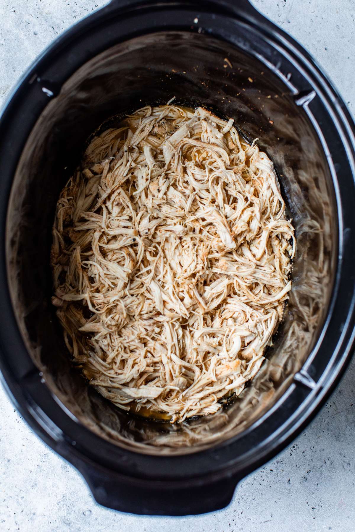 Shredded chicken in a slow cooker.