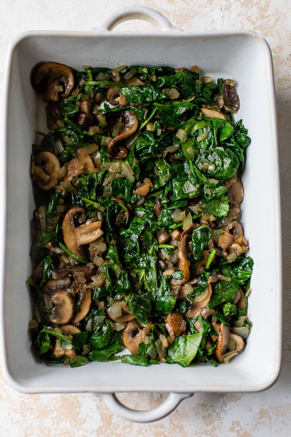 Spinach and mushrooms in the bottom of a casserole dish.