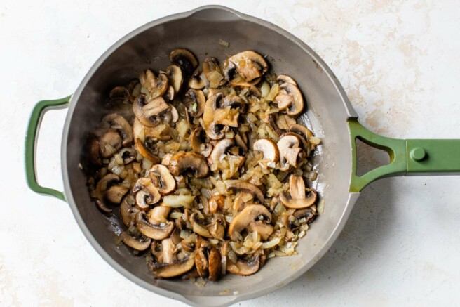 Mushrooms sautéing in a pan.