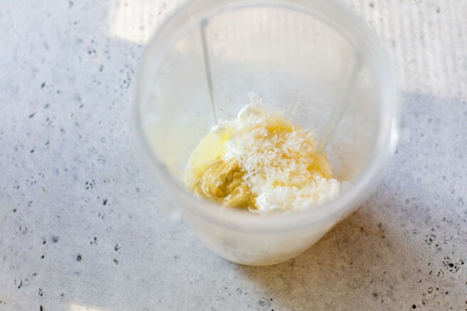 Adding Greek yogurt, parmesan cheese and dijon mustard to a small food processor.